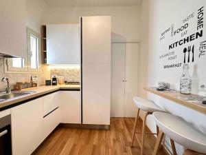 a kitchen with white cabinets and a counter with chairs at Lella suite home in Lecce