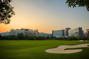 un campo de golf verde con edificios en el fondo en Renaissance Suzhou Taihu Lake Hotel en Suzhou