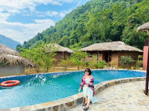 a woman sitting next to a swimming pool at Bac Ha Lodge Retreat in Bắc Hà