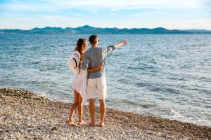 a man and a woman standing on the beach at Hotel Pinija in Petrcane
