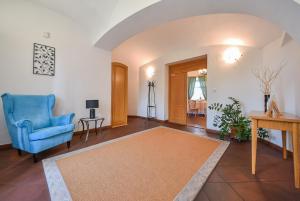 a living room with a blue chair and a rug at Kaštieľ Sokoľany in Sokoľany