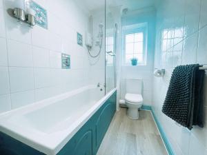 a white bathroom with a tub and a toilet at Buckingham House - Charming 2-bedroom House with garden and parking in Buckingham
