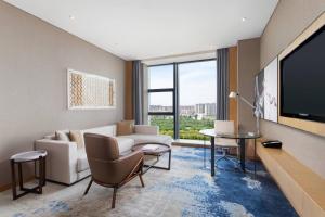 a living room with a couch and a tv at Courtyard by Marriott Zhengzhou Airport in Zhengzhou