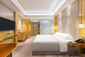 a bedroom with a large white bed and a television at Courtyard by Marriott Nanchang in Nanchang