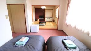 a bedroom with two beds and a hallway with a room at Felse Inn Gakusui in Hakuba