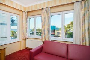 a living room with a red couch and windows at Strandvilla Viktoria - Anbau vom Strandhotel Preussenhof in Zinnowitz