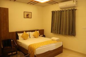 a bedroom with a bed with yellow sheets and a window at Hotel JMB in Jodhpur