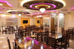 ein Restaurant mit Holztischen und -stühlen und lila Beleuchtung in der Unterkunft Hotel JMB in Jodhpur