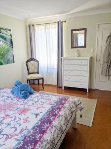ein Schlafzimmer mit einem Bett, einer Kommode und einem Stuhl in der Unterkunft Bright & breezy chalet close to town & beach in Dunsborough