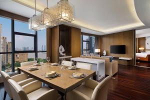 a dining room with a table and chairs and a bedroom at Courtyard by Marriott Hangzhou Qianjiang in Hangzhou