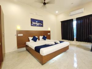 - une chambre avec un grand lit et des oreillers bleus dans l'établissement PV Resort - Auro Beach, à Auroville