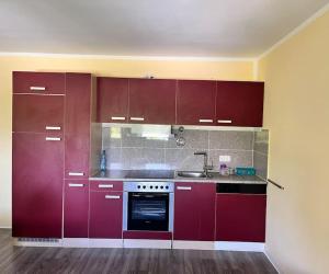 cocina con armarios rojos, fregadero y fogones en Apartment in Gilching en Gilching