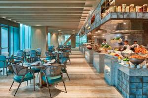 um restaurante com mesas e cadeiras e pessoas na cozinha em Hangzhou Marriott Hotel Qianjiang em Hangzhou