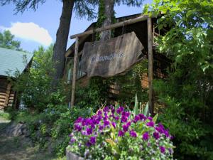 una señal para una cabaña de madera con flores púrpuras en Madarao Vacance Village en Iiyama