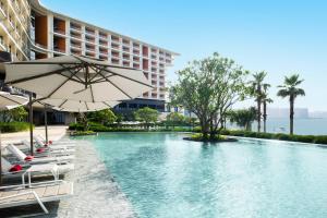 a pool at a hotel with chairs and an umbrella at Le Méridien Xiaojing Bay in Huizhou