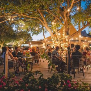 een groep mensen die aan tafel zitten in een patio met verlichting bij Blue Bay Curaçao Golf & Beach Resort in Willemstad