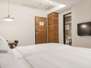 1 dormitorio con 1 cama blanca y TV en CHECK inn Express Taipei Station, en Taipéi