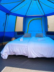 a bed in a tent with a blue canopy at Luxury tent - Villmarkseventyret in Håtvet