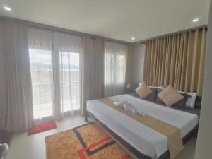 a bedroom with a large bed and large windows at RC Villas and Resorts in El Nido