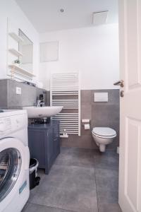 ein Badezimmer mit einem Waschbecken, einem WC und einer Waschmaschine in der Unterkunft City Park Apartments - #16, #18 & D - Moderne Apartments & Suiten im Zentrum in Leipzig