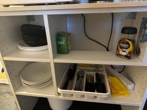 a cupboard with plates and dishes and a shelf with food at Center apartments in Oslo