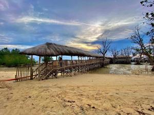 drewniana przystań z dużym parasolem na plaży w obiekcie Kaway Resort & Spa w mieście Tabuelan