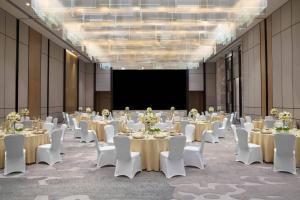 una sala conferenze con tavoli, sedie bianche e schermo di Courtyard by Marriott Shenzhen Bao'an a Bao'an