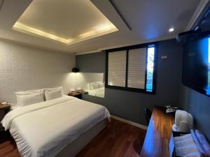 a bedroom with a large white bed and a window at Jjak motel in Changwon