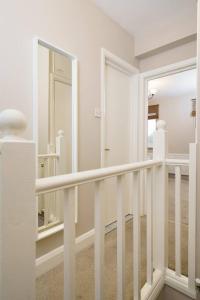 a white hallway with a staircase with a mirror at Astrid by Oval in London