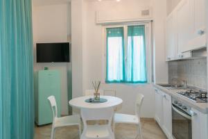 een keuken met een witte tafel en stoelen en een koelkast bij Casa dell'elba in Piombino