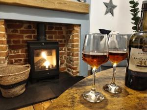 two glasses of wine sitting on a table in front of a fireplace at Martha's cottage by the sea in Gorleston-on-Sea