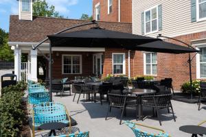 een patio met tafels en stoelen en een parasol bij TownePlace Suites Chicago Lombard in Lombard