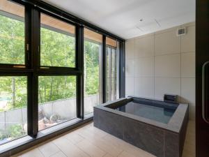bañera grande en una habitación con ventanas en Niseko Kyo en Niseko