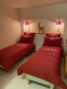 1 dormitorio con 2 camas con edredones rojos y una estatua de ciervo en gîte à la montagne au calme, 