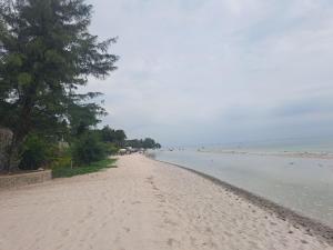 a sandy beach with trees and the ocean at Baan Sandao Unit 303 in Hua Hin