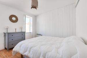 ein weißes Schlafzimmer mit einem großen Bett und einem Fenster in der Unterkunft Douce escapade sur l ile de Re avec Hoomy in La Flotte