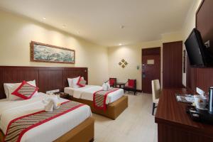 a hotel room with two beds and a flat screen tv at Grand Istana Rama Hotel in Kuta