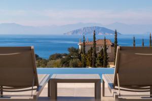 two chairs and a pool with a view of the ocean at Villa Alchaca - New Magnificent Villa with Infinity Pool & Tennis in Kilada