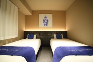 two beds in a room with blue pillows at Dynasty Hotel & Resort Osaka in Osaka