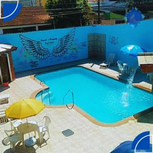 a large swimming pool with a yellow umbrella and chairs at Hostel&Pousada Equilíbrio in Praia Grande