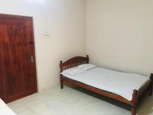 Habitación pequeña con cama y puerta de madera en Senani Villa, en Hungama