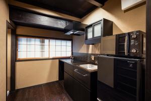 a small kitchen with black cabinets and a sink at Rinn Premium Machiya Koki in Kyoto
