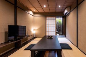 een woonkamer met een tafel en een televisie bij Rinn Premium Machiya Koki in Kyoto