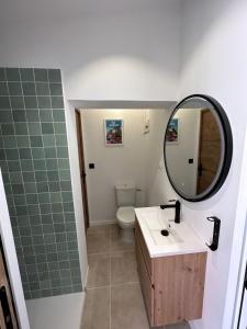 uma casa de banho com um lavatório, um espelho e um WC. em VILLA NOAVA em La Crau