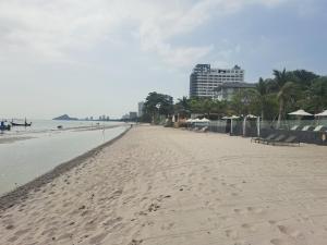 een leeg strand met een gebouw op de achtergrond bij Baan Sandao Unit 303 in Hua Hin