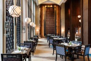 una sala da pranzo con tavoli, sedie e lampadari a braccio di Changzhou Marriott Hotel a Changzhou