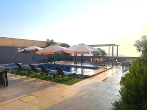 ein Pool mit Tischen, Stühlen und Sonnenschirmen in der Unterkunft Zoom Chalets in Amman