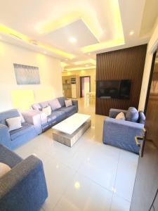 Zoom Chalets في عمّان: غرفة معيشة مع أرائك زرقاء وتلفزيون بشاشة مسطحة