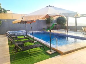 ein Pool mit Stühlen und einem Sonnenschirm neben einem Pool in der Unterkunft Zoom Chalets in Amman