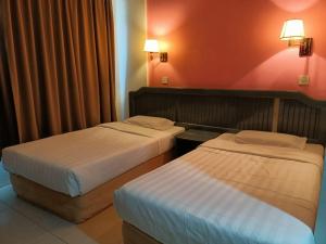 duas camas num quarto de hotel com paredes vermelhas em Monaco Hotel em Tawau